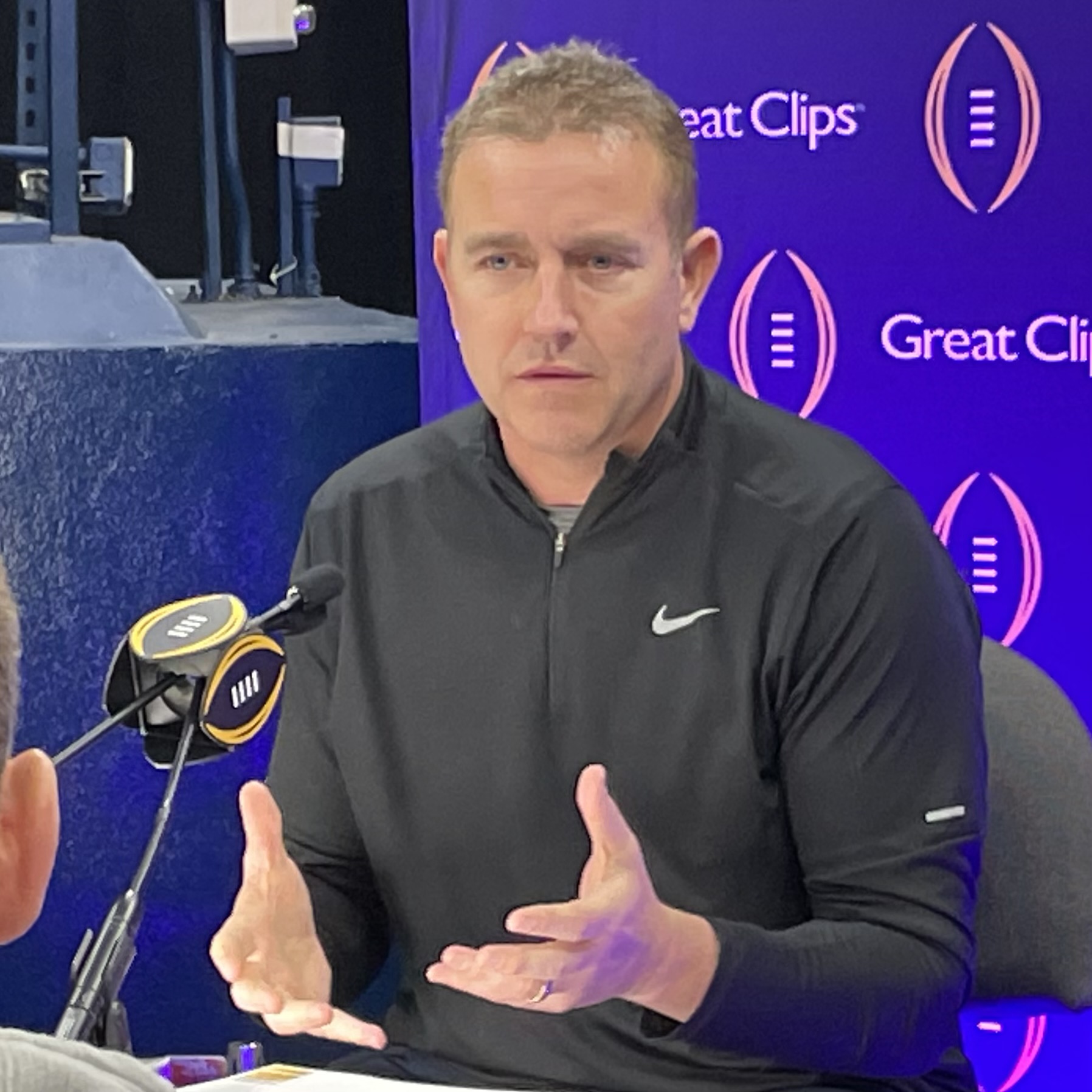 Kirk Herbstreit on the sideline of a football game holding a microphone